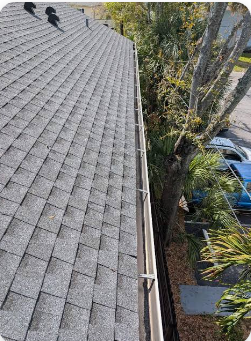 Clear residential gutter running along a shingle roofline